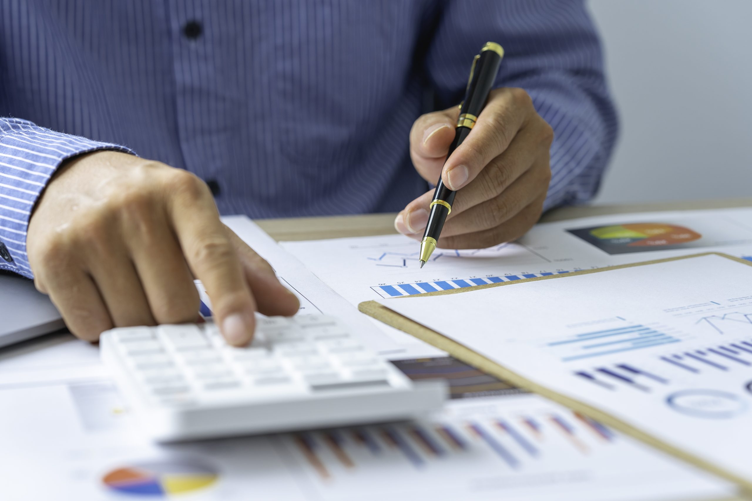 Close up account man hand using calculator for calculate and writing make a note with pen, financial reporting and business performance to check investment results