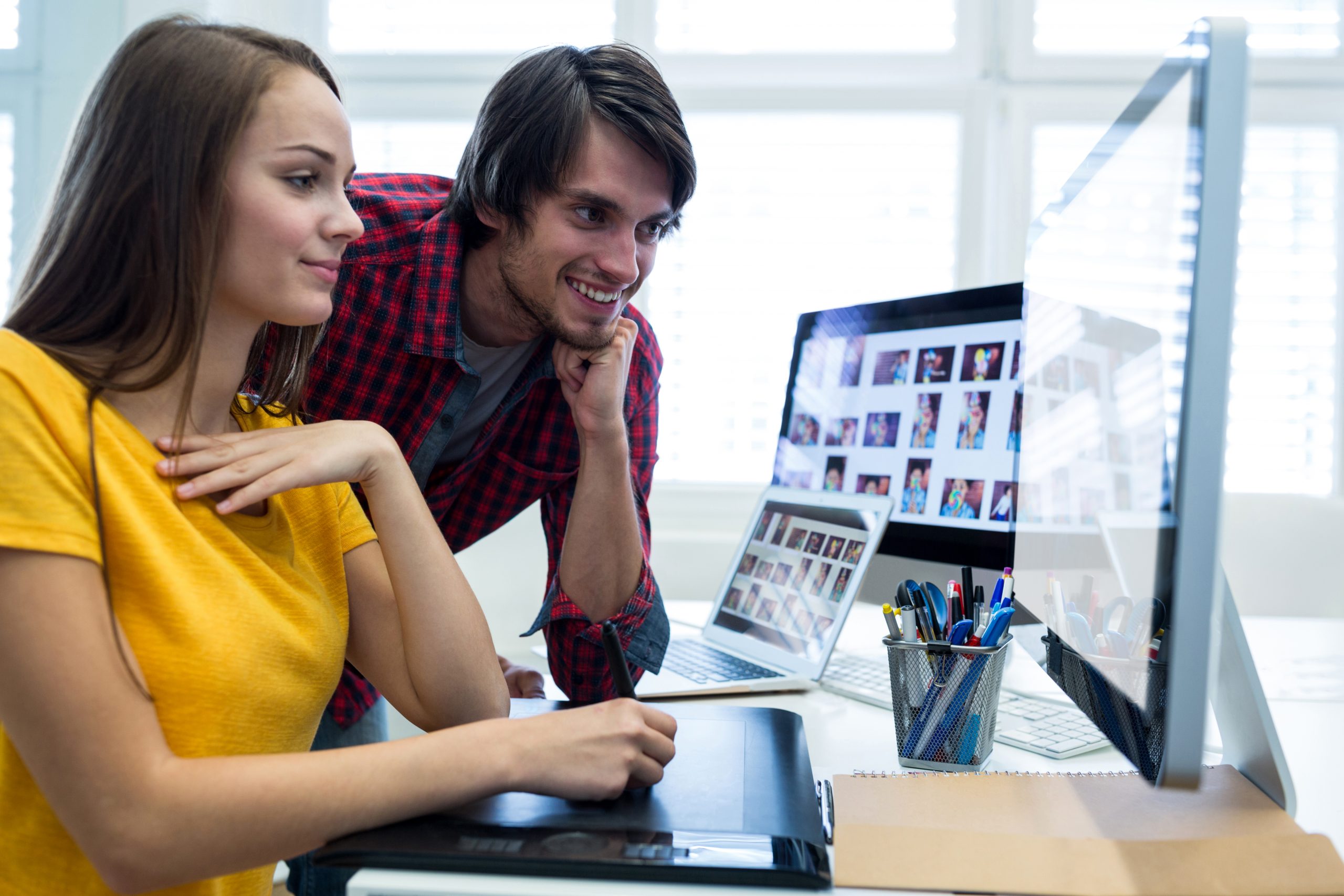 Male and female graphic designers using graphics tablet in office