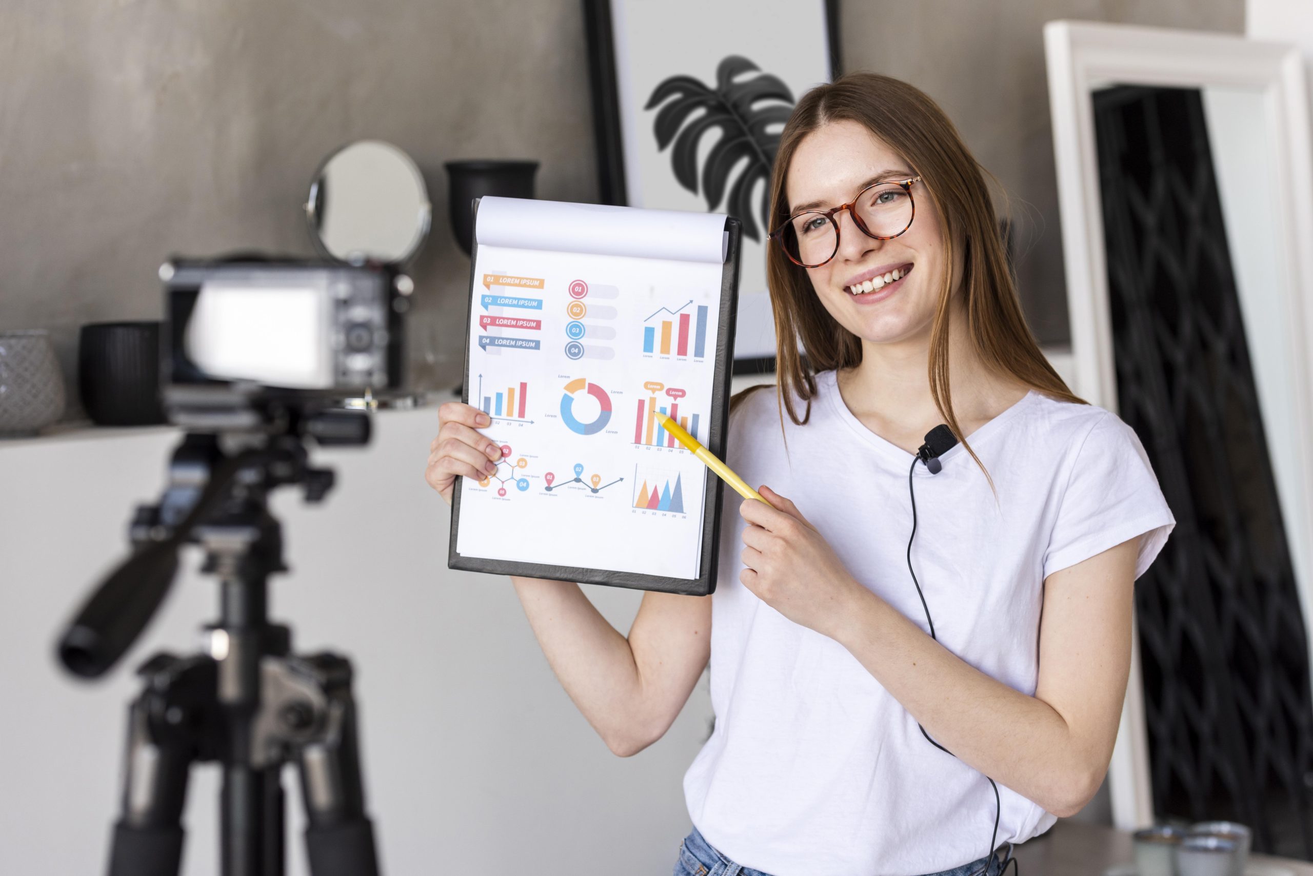 young-blogger-recording-with-professional-camera-holding-clipboard-with-graphics